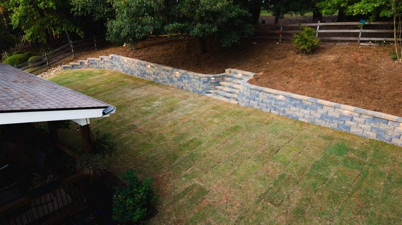 finished retaining wall with built-in lights and steps above new sod